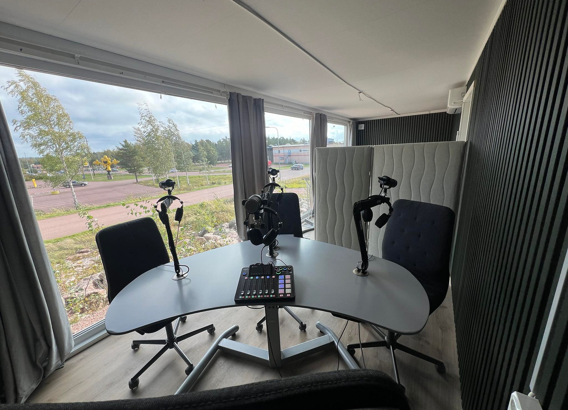 Poddboxens studio med mikrofoner, akustikpaneler och utsikt över Mariehamn