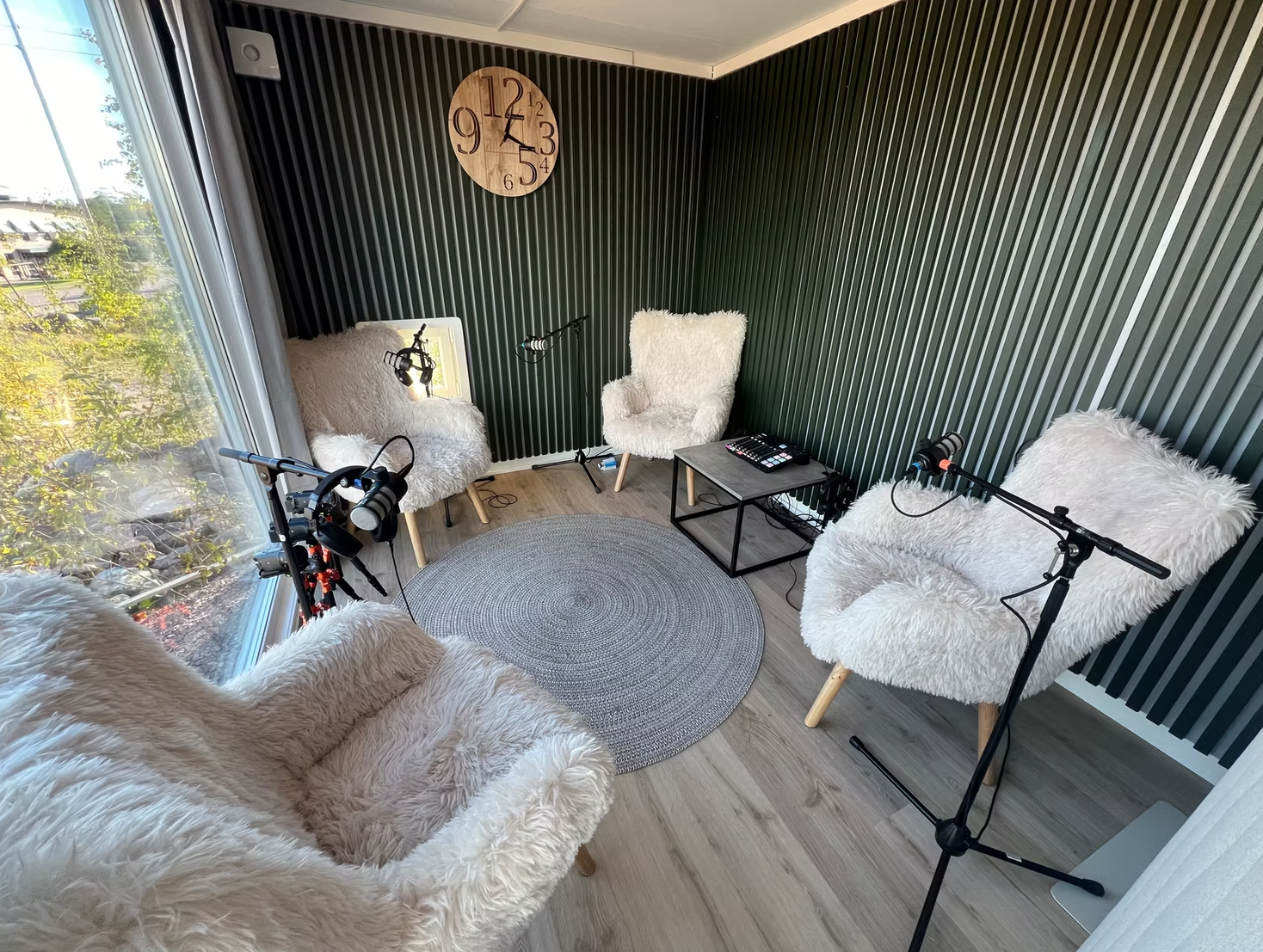 Poddboxens inspelningsyta med mikrofoner, bekväma fåtöljer och grön akustikpanel